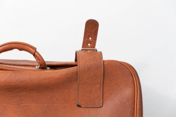 istock Antique clasp on a brown retro suitcase, near the white wall. 1385669929