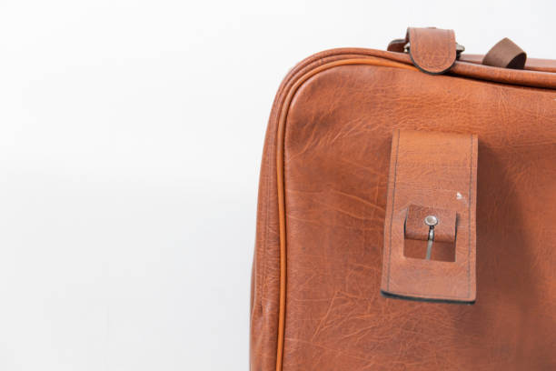 istock Antique clasp on a brown retro suitcase, near the white wall. 1385669931