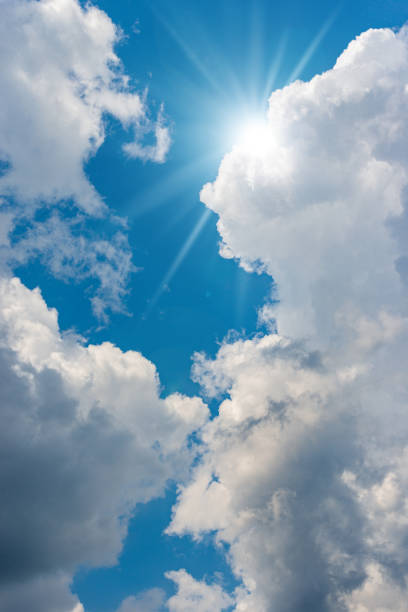 Beautiful blue sky with white cumulus clouds and sun rays (sunbeams). Backlight photography.