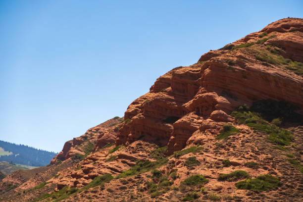 istock Red eroded mountains with blue sky background for wallpaper design. Nature scenic background. Sandstone erosion process due to wind and rains. Dzhuuku gorge. 1385678627