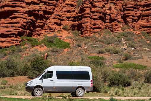 4x4 off-road van mersedes-benz sprinter with red mountains on background. Offroad camper, caravanning concept. Overland lifestyle. Vanlife concept. Summer road trip. 25.07.2021 Dzuuku, Kyrgyzstan.