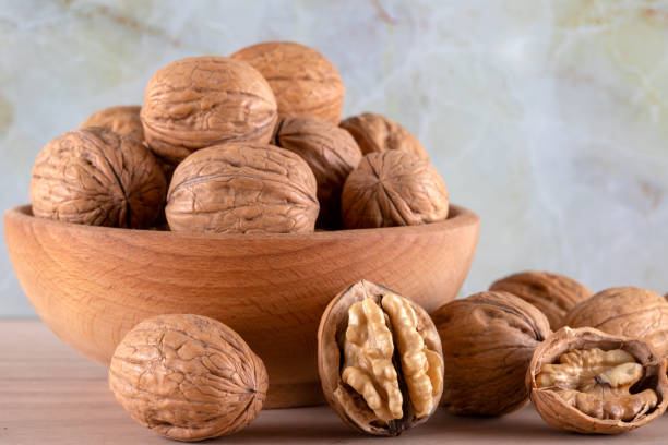 istock Walnut kernels and whole walnuts on wooden background 1385678888