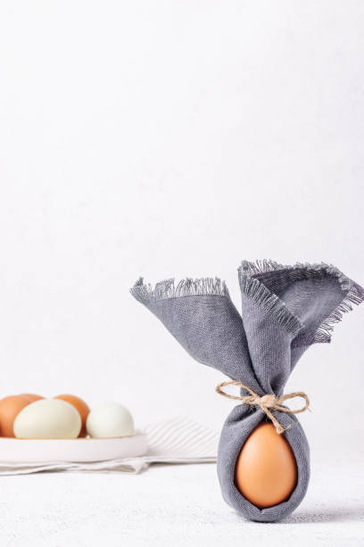 istock Easter egg decorated with a napkin in the shape of a bunny on a white concrete background 1385680104