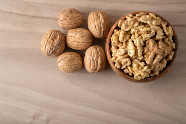 istock Bowl of walnuts and whole walnut kernels on wooden background 1385680301