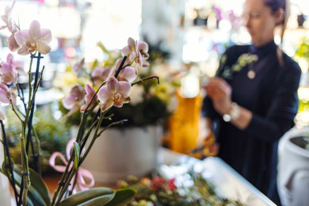 Concept of flower arranging, making beautiful bouquets with your own hands. Shot of unrecognizable woman entrepreneur arranging bouquet of a fresh flowers and plants at her workshop studio with copy space on desk.