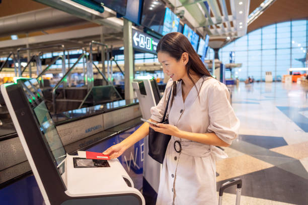 istock Woman using self service check -in with smart phone in airport. 1385688696