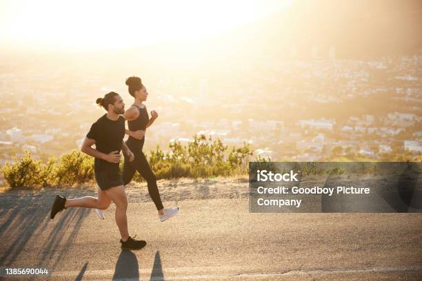 Two Fit Young People Jogging Together Along A Scenic Road Stock Photo - Download Image Now