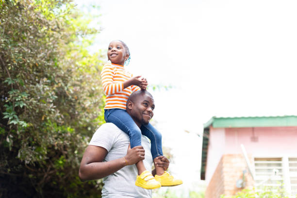 istock Father carrying daughter on shoulders in garden 1385693452