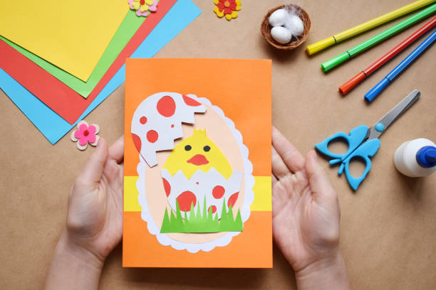 Making of handmade Easter decoration. Child made greeting card in egg shape. Childrens DIY concept, gift with your own hands. Hobby, paper crafts at home or  in kindergarten.