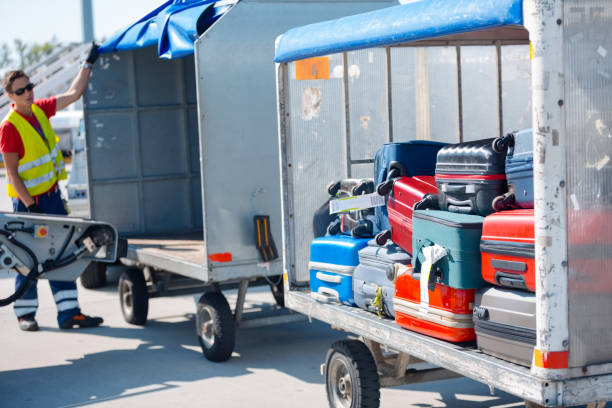 Outdoor shot of luggage transporting to the airplane. Airport ground crew at work.