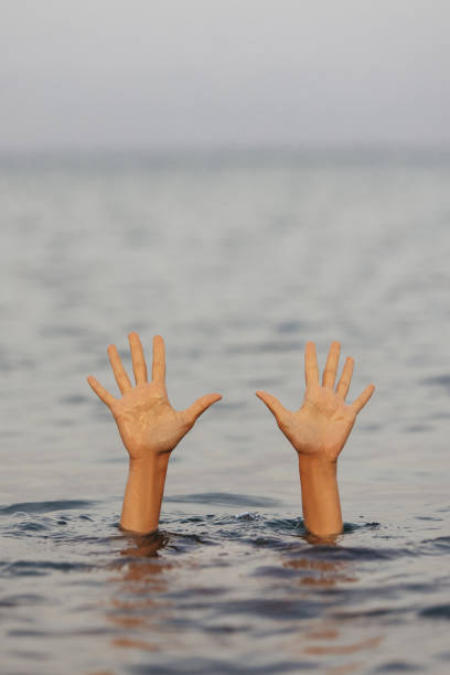 istock Unrecognizable woman hands waving for help, drowning into the sea 1385696626