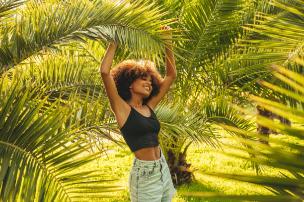 istock Pretty young afro woman among palm trees 1385697043