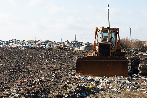 An orange earthmover amidst a landfill. Environmental pollution concept
