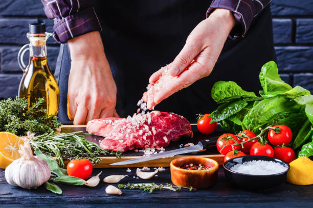 istock chef is sprinkling salt on strip loin steaks 1385700750