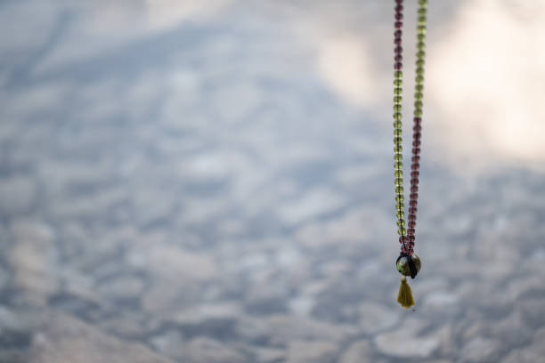 mala beads hanging above clear water with rocks on bottom
