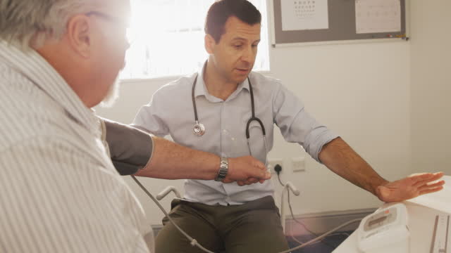 Male doctor checking blood pressure of senior patient in doctor's office