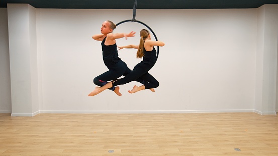 Aerial acrobat in the ring. \nA woman performs the acrobatic elements in the air ring.