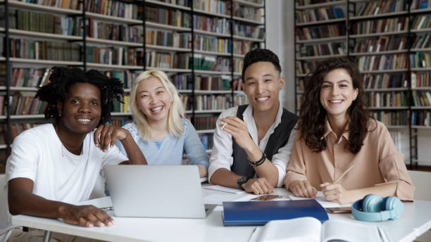 istock Portrait of smiling young students sitting at table. 1385706049