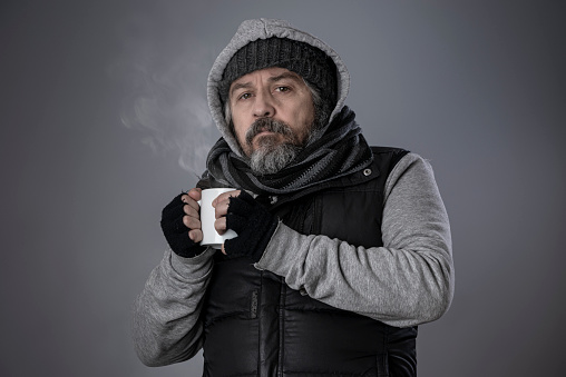 Homeless man drinking hot coffee to warm up.