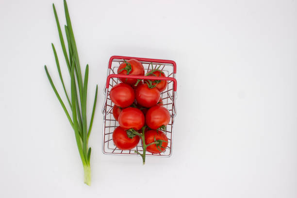 Green onions and tomatoes in basket on white background