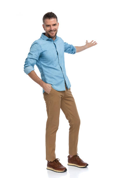 istock handsome bearded man with hand in pocket welcoming and inviting to side 1385708051