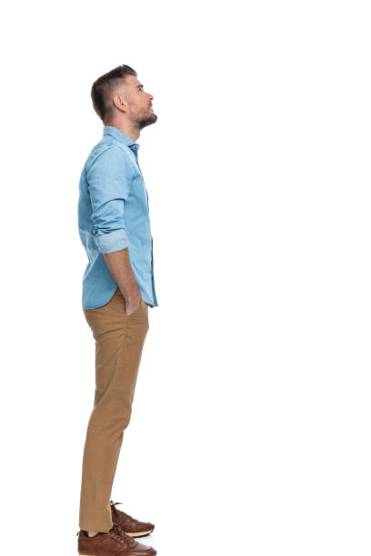 attractive man in his forties standing in line with hands in pockets and looking up on white background in studio