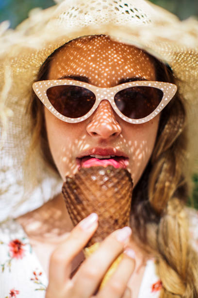 Gorgeous young woman outdoors enjoying while eating ice cream at sunny day. She is tourist on vacation Greece islands and looks happy and carefree