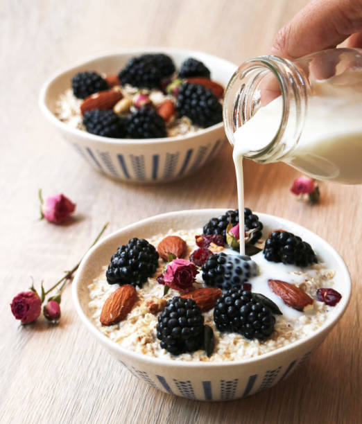 Healthy oat meal cereal breakfast Healthy oat meal cereal breakfast with blackberries fruit and almonds with whole grains, bottle of milk pouring into a bowl, clean food concept oat wheat oatmeal cereal plant stock pictures, royalty-free photos & images