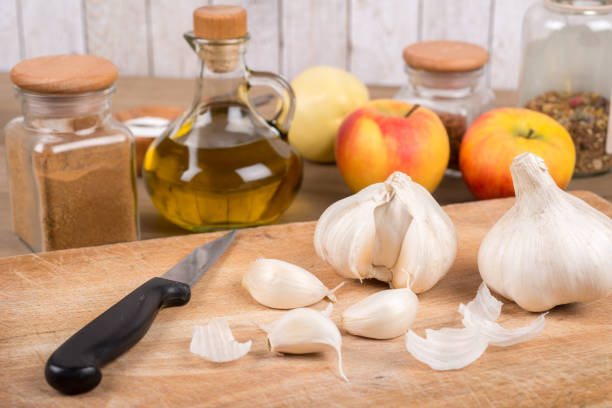 Garlic on a wooden board with kitchen utensils in the background