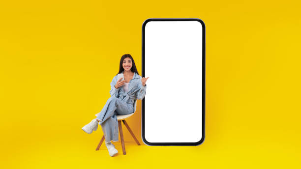 istock Happy lady using mobile phone pointing at gadget at studio 1385712605