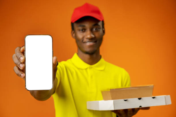 istock African courier guy showing smartphone with blank screen and holding box in studio 1385716208