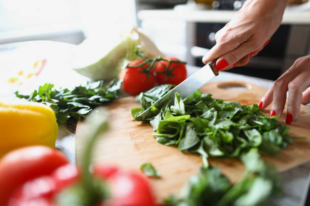 istock Woman cuts lettuce leaves with kitchen knife 1385716916