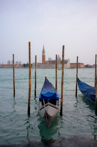 Gondolas tied up on the side of the Grand Canal in Venice. Across the lagoon we see the iconic shape of the Church of San Giorgio Maggiore