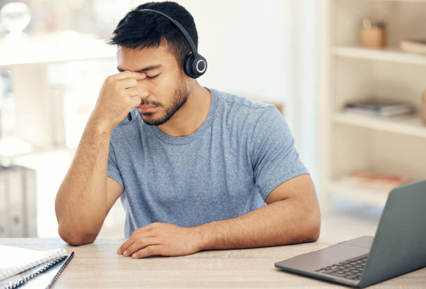istock Shot of a young male call center agent suffering from a headache while at work 1385717599