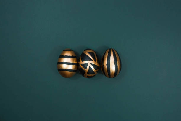 istock Gold, black, white eggs on a trendy emerald background. Geometry. The minimal concept. Top view. An Easter card with a copy of the place for the text. 1385720683