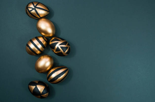 istock Gold, black, white eggs on a trendy emerald background. Geometry. The minimal concept. Top view. An Easter card with a copy of the place for the text. 1385720686