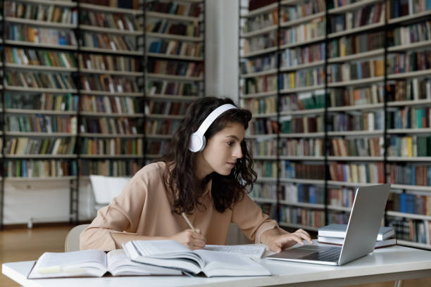istock Happy pretty millennial Hispanic woman e-learning in library. 1385721345