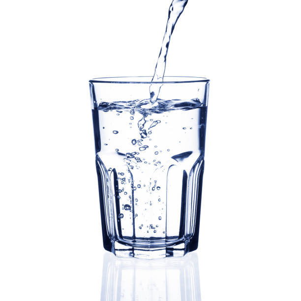 istock Water pouring into glass on white background. 1385723741