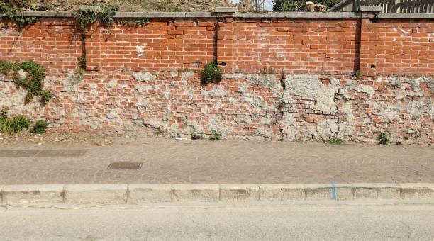 istock Grunge boundary brick wall, porphyry sidewalk and asphalt road in front. 1385724775