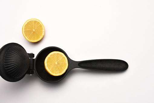Lemon squeezer and lemon slices on the white background with copy space