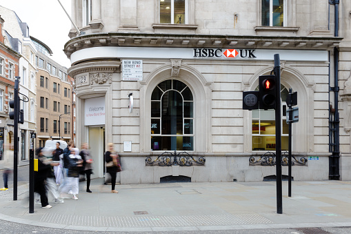 London, UK - 14 March, 2022: blurred motion of people walking outside a branch of an HSBC bank outdoors on a city street in central London, UK.