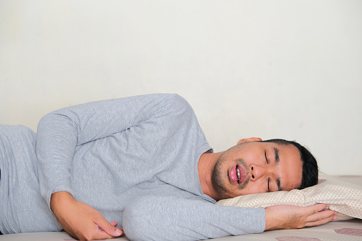 Vista lateral del hombre asiático adulto que duerme profundamente photo