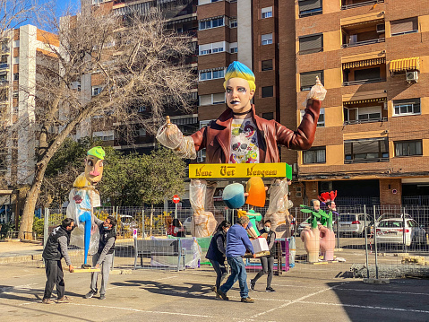 Valencia, Spain - March 13, 2022: Group of people carrying ninots to place them in the street. These are the sculptures that are going to be burned at the last day of Las Fallas annual celebration
