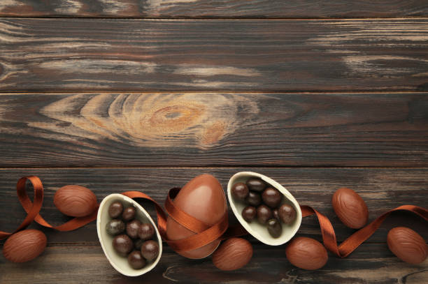 istock Easter composition with chocolate eggs and brown ribbon on brown wooden background. 1385731340