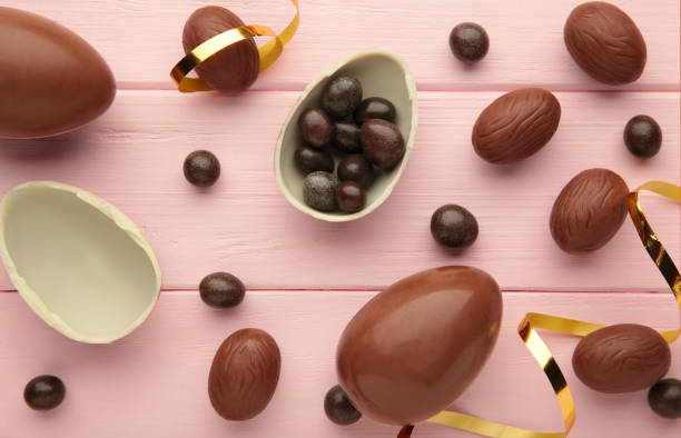 istock Easter composition with chocolate eggs and brown ribbon on pink wooden background. 1385731425