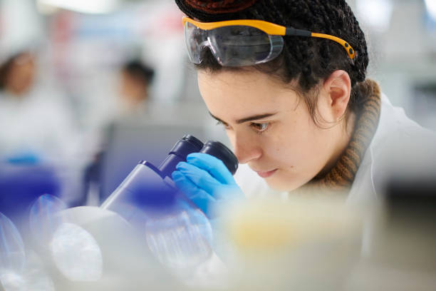 istock young female biochemist with microscope 1385731560