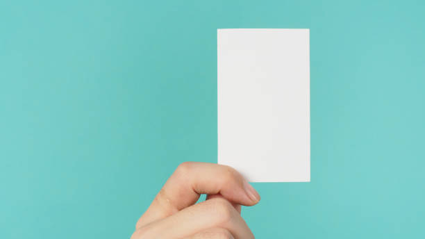 istock Empty space for text.Male hand holding white blank card isolated on mint green or Tiffany Blue background. 1385733925