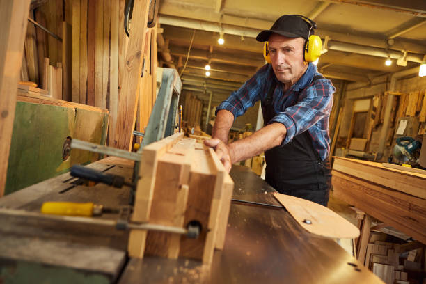 istock Senior carpenter in uniform works on a woodworking machine at the carpentry manufacturing 1385734005
