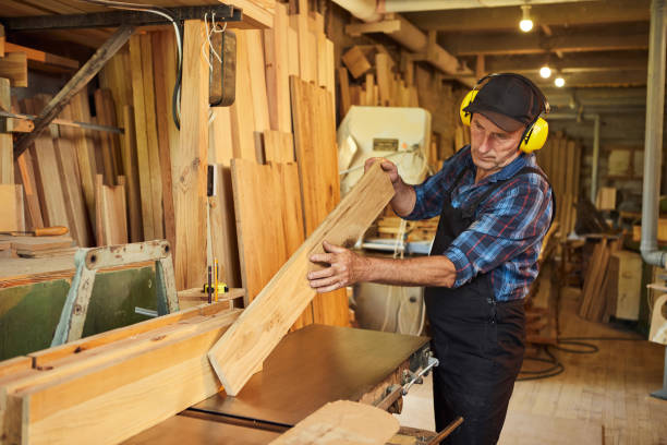 istock Senior carpenter in uniform works on a woodworking machine at the carpentry manufacturing 1385734113
