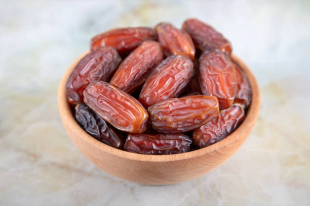 istock Bowl of dates fruit on colorful marble background, top view 1385736396